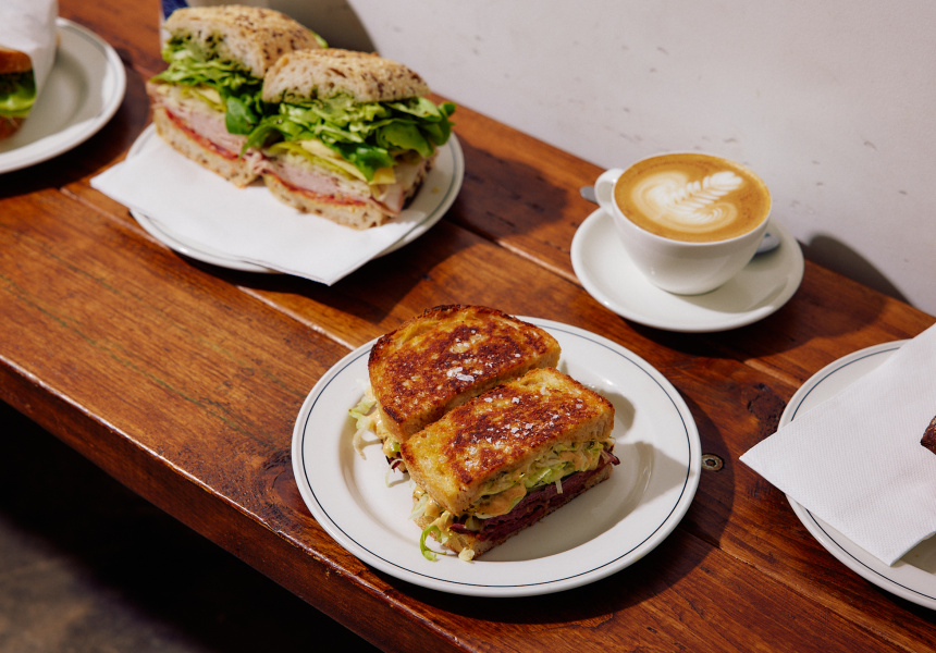 Toasted sandwiches and latte art on a timber table at Superdays Coffee